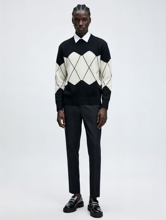 Man wearing a black and white argyle sweater with black pants on a white background